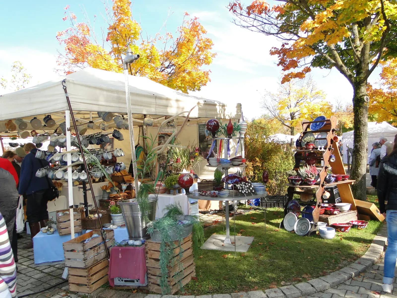 Marktstand mit Keramik zwischen herbstlich gefärbten Bäumen