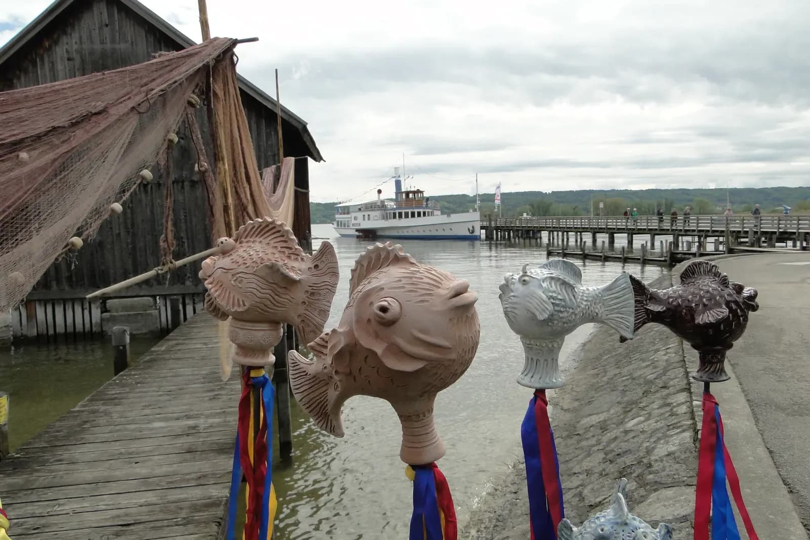 Keramikfische mit bunten Bändern am Steg des Ammersees
