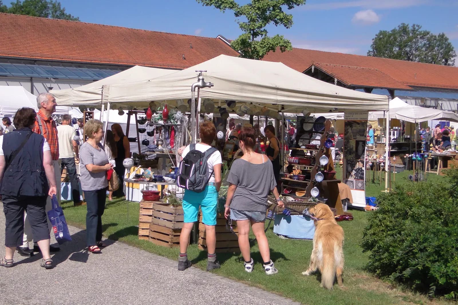 Besucher vor dem Marktstand mit Keramik unter dem Pavillon